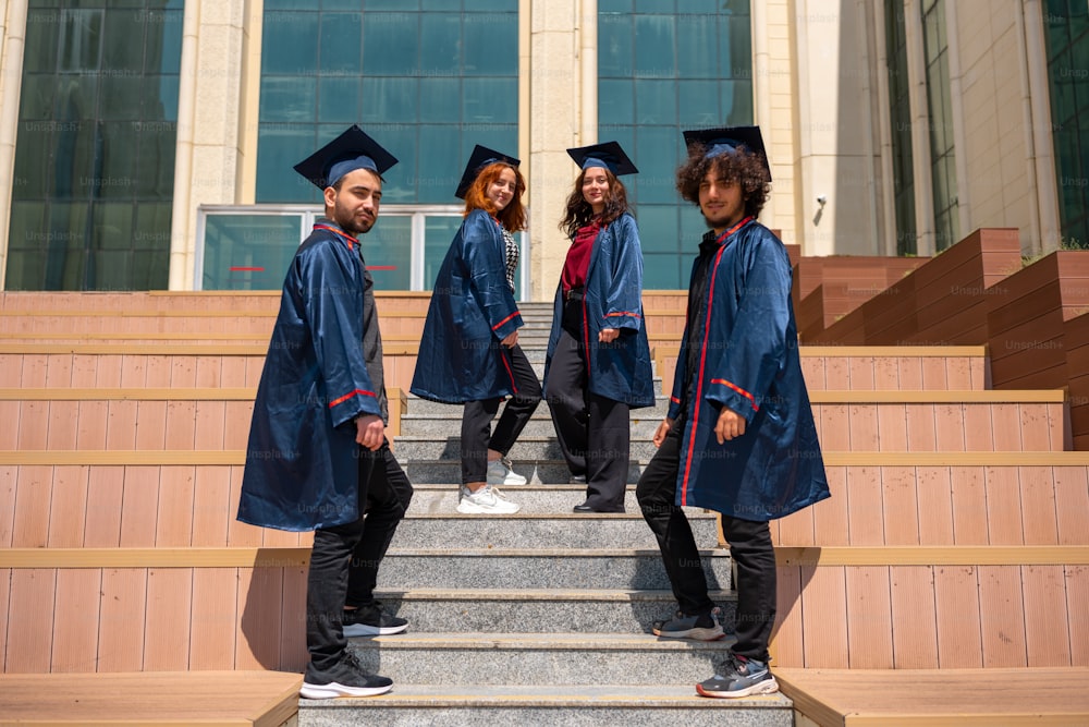 Un grupo de personas en vestidos de graduación de pie en los escalones