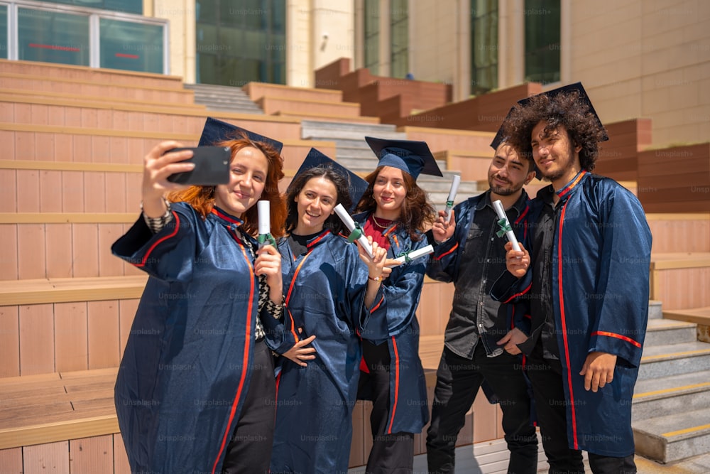 携帯電話で写真を撮る卒業生のグループ