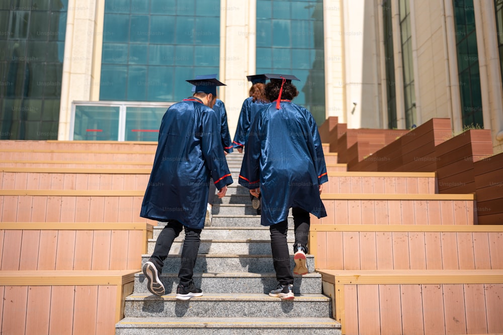 two people in graduation gowns walking down a flight of stairs