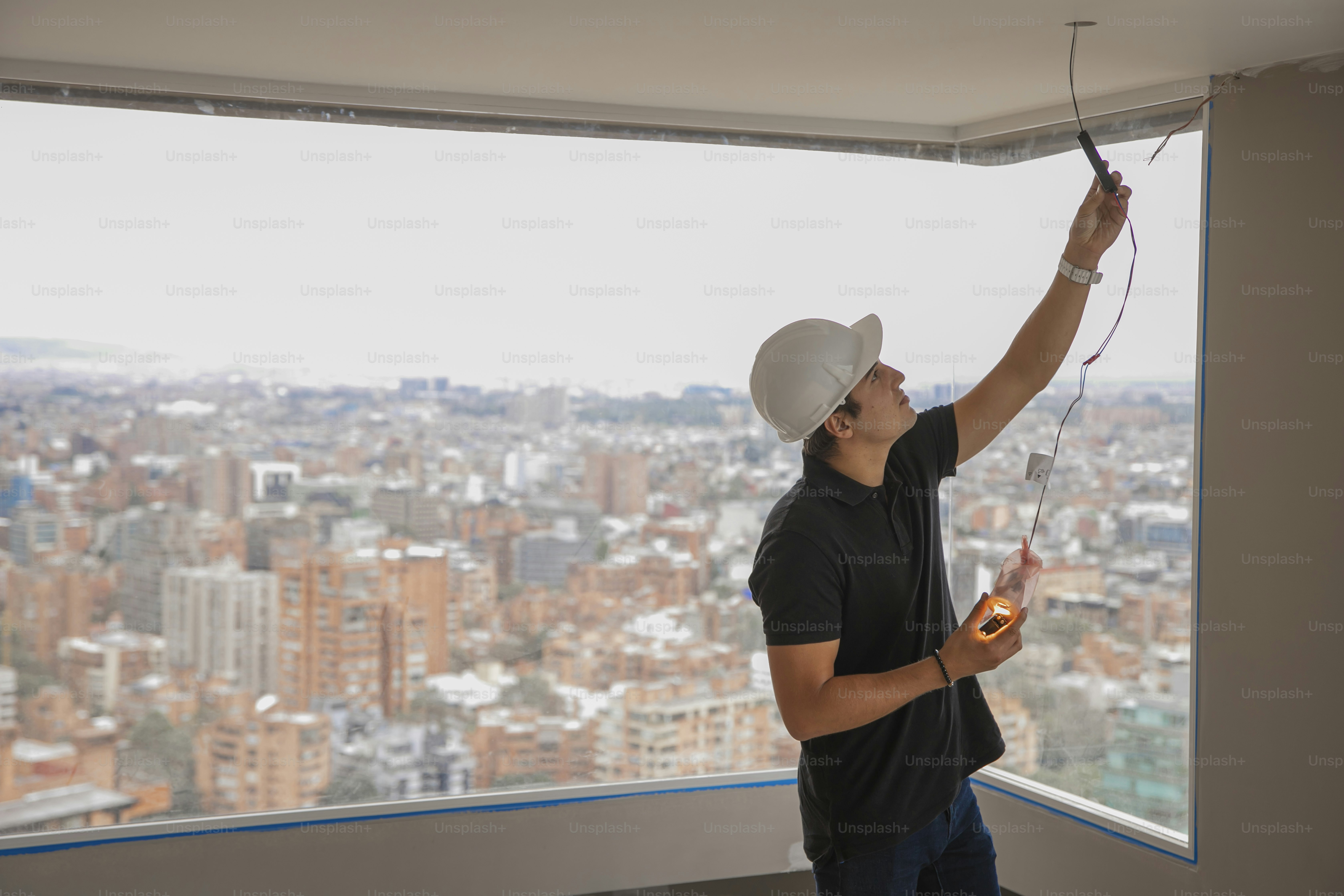 a man in a white hat and black shirt is painting a window