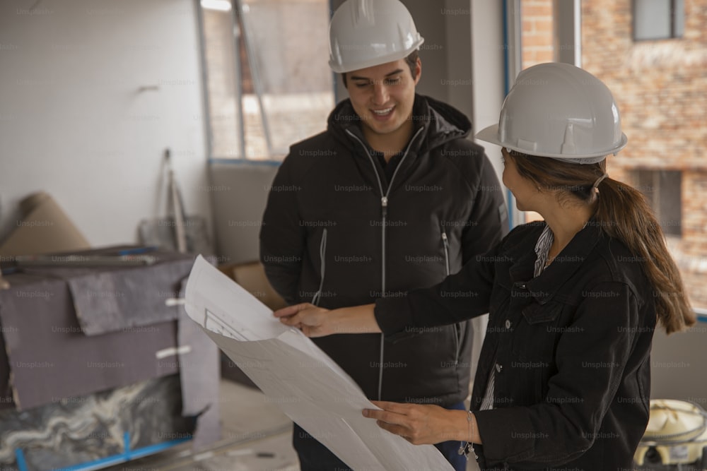 a man and a woman in hard hats looking at a blueprint