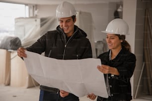 a man and woman in hard hats looking at a blueprint