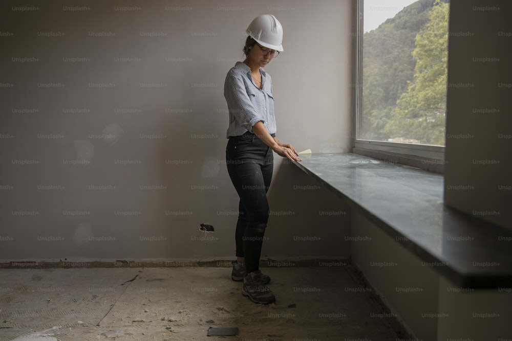 a woman wearing a hard hat standing next to a window