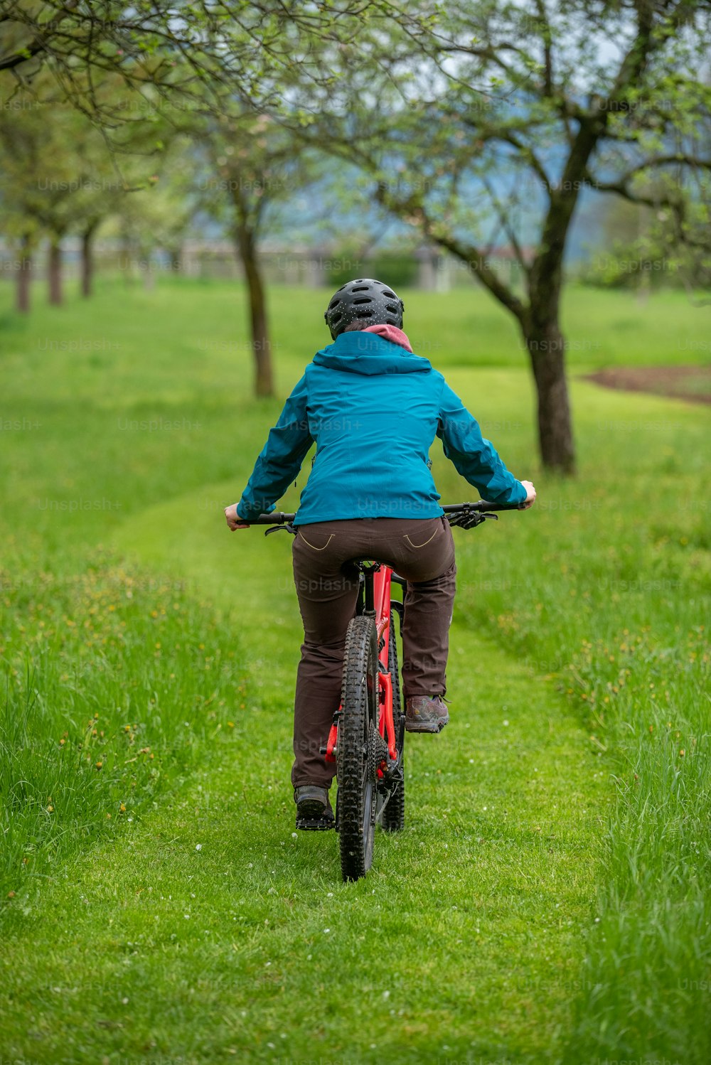 a woman riding a bike down a lush green field