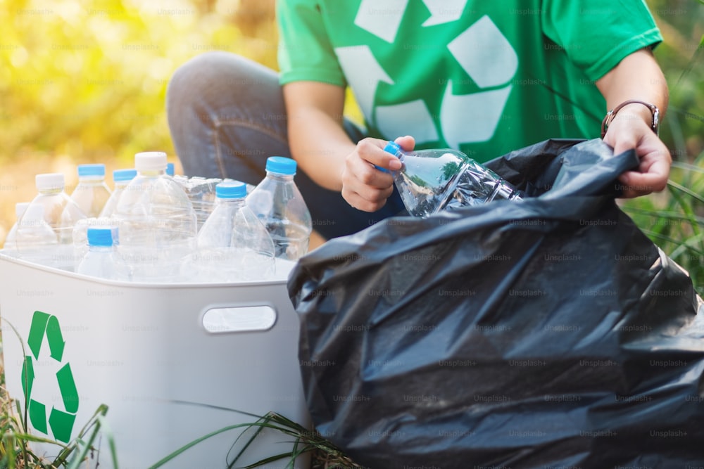 Eine Frau, die Müll-Plastikflaschen in eine Kiste und eine Plastiktüte für das Recycling-Konzept aufnimmt