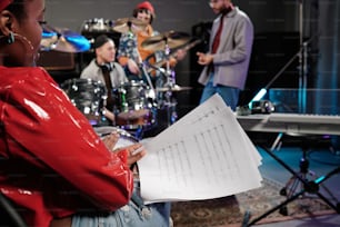 a woman holding a sheet of paper in front of a band