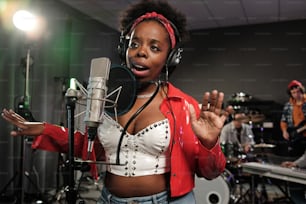 uma mulher com uma jaqueta vermelha e fones de ouvido em frente a um microfone