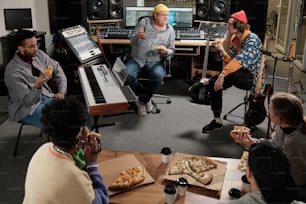 a group of people sitting around a table eating pizza