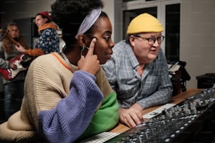 a woman sitting in front of a keyboard next to a man