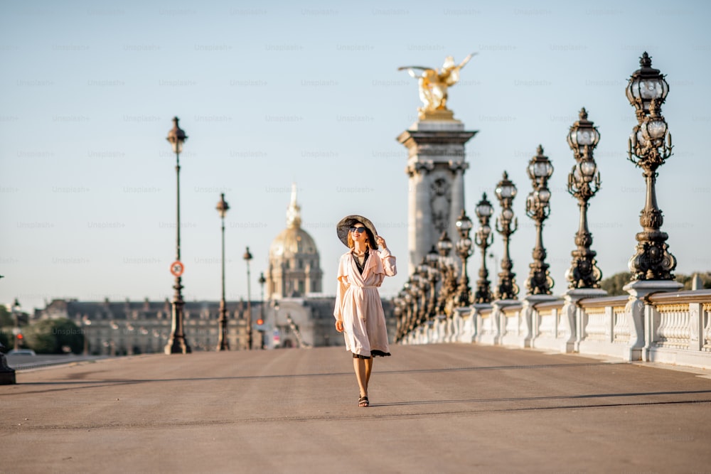 Vista sobre el famoso puente Alexandre con una hermosa mujer caminando durante la vista de la mañana en París