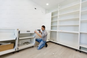 Homem montando armário de cozinha usando chave de fenda