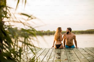 Couple at wooden pier on river at hot summer day