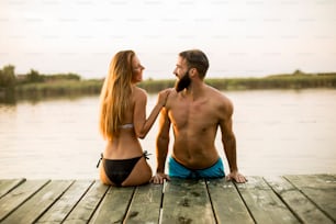 Couple at wooden pier on river at hot summer day