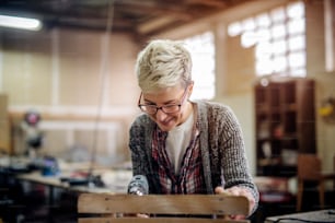 Close up of woman making a chair. Carpenter workshop interior.