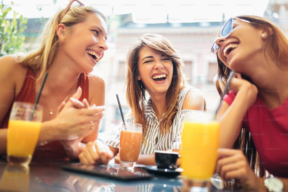 Three beautiful friends in a cafe having fun