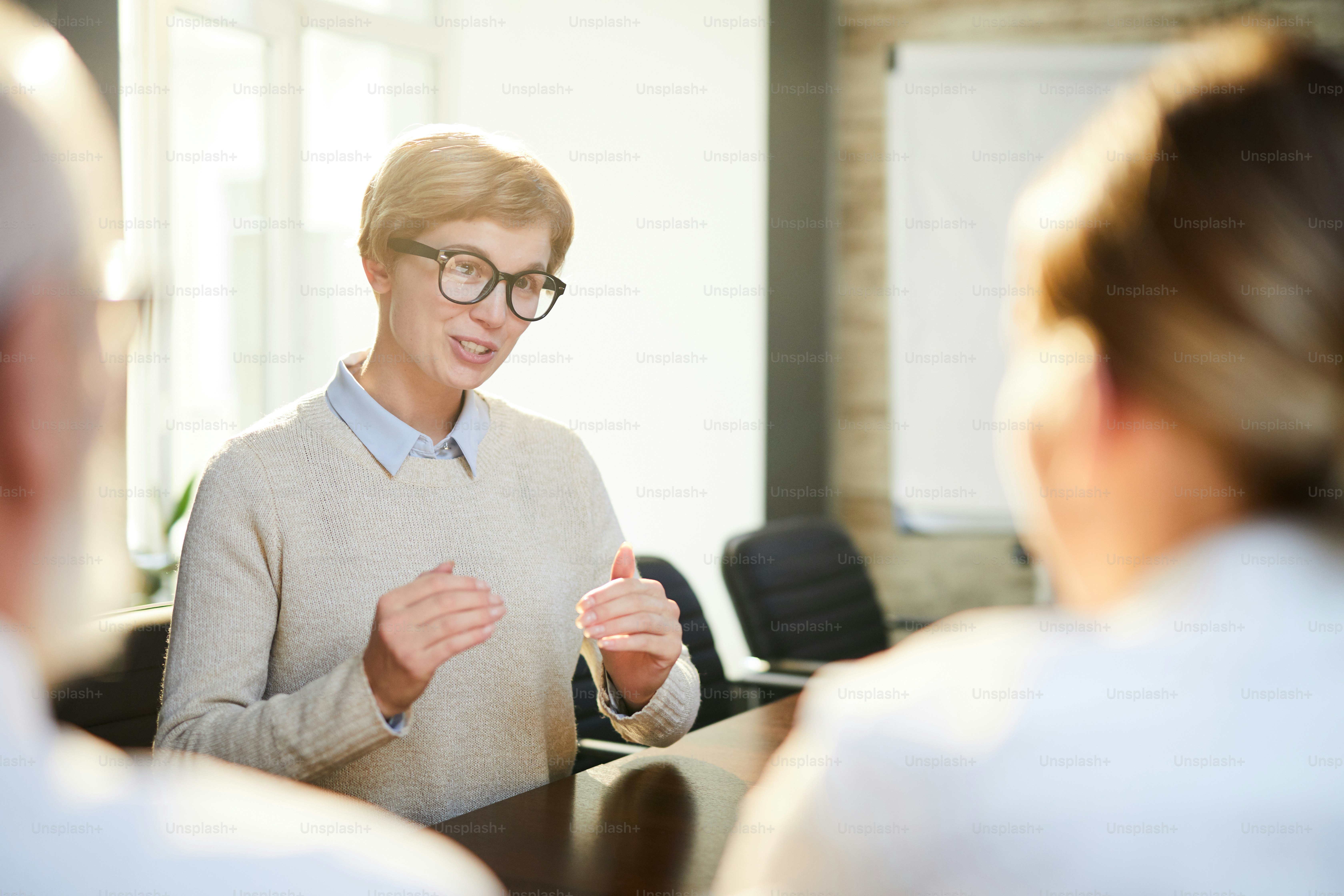 Young female applicant explaining something while answering question of employers during interview