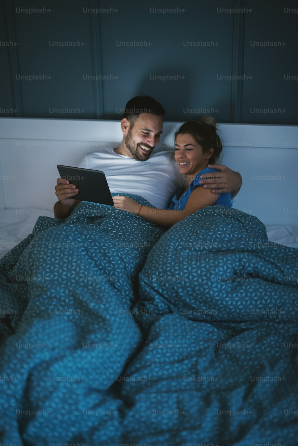 행복한 편안한 만족 한 커플은 침대에 누워 인터넷을 통해 서핑을합니다.