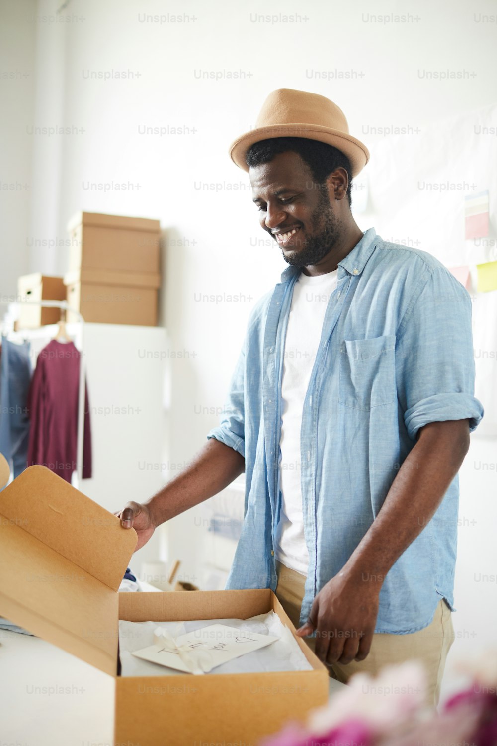 Owner of modern fashion studio or atelier packing one of orders into box before sending it to client