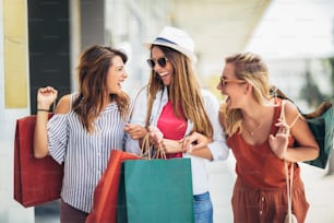 Duas mulheres felizes com sacolas de compras desfrutando em compras, haning diversão na cidade.