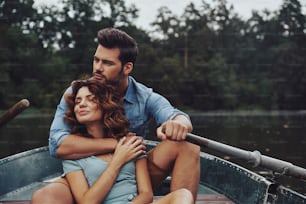 湖でロマンチックなデー�トを楽しみながら抱きしめて目をそらす美しい若い夫婦