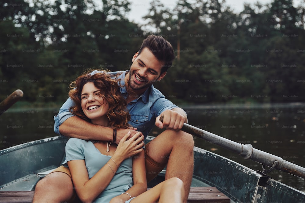 Beautiful young couple embracing and looking away while enjoying romantic date on the lake