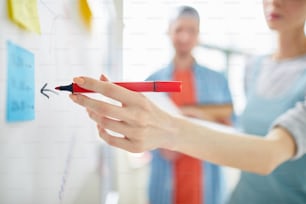 Close-up do gerente profissional desenhando com caneta marcadora no quadro branco enquanto oferece estratégia de marketing na reunião