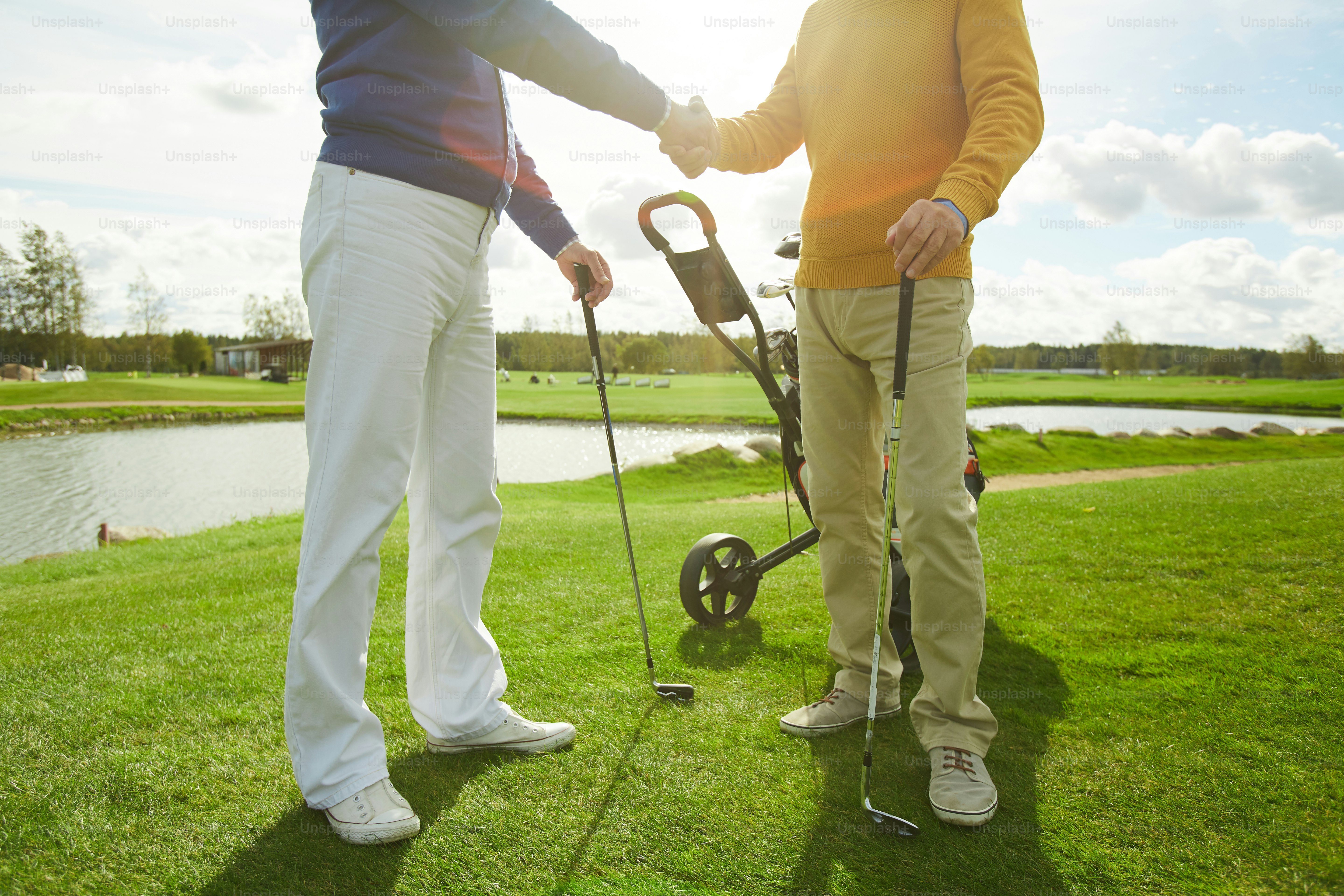 Two active men shaking hands while greeting one another before game of golf
