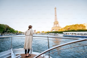 パリの夕暮れ時にボートからエッフェル塔のある川沿いの美しい風景を楽しむ若い女性。コピー用スペース付きのワイドビュー
