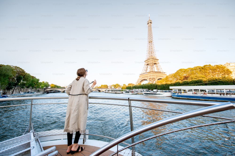 Mujer joven disfrutando de una hermosa vista del paisaje en la orilla del río con la torre Eiffel desde el barco durante la puesta de sol en París. Vista amplia con espacio de copia