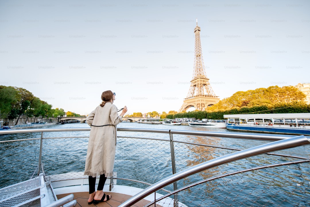 Young woman enjoying beautiful landscape view on the riverside with Eiffel tower from the boat during the sunset in Pari