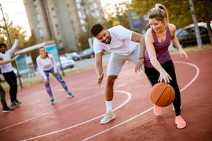 Gruppo di giovani multietnici che giocano a basket in campo