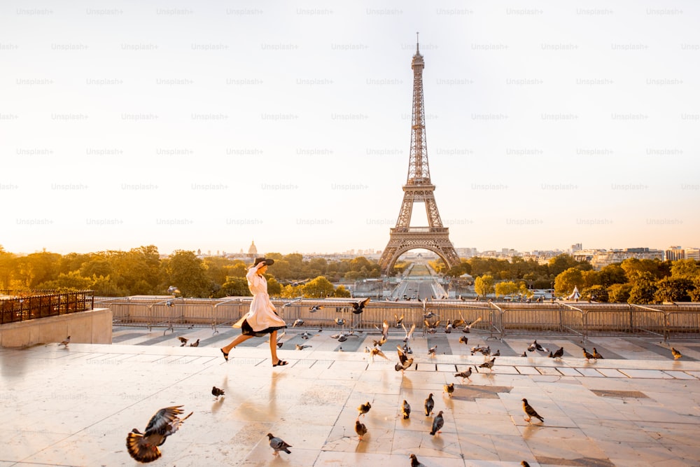 파리의 이른 아침 에펠탑에서 멋진 전망을 감상하며 유명한 광장에서 비둘기를 흩뿌리는 여자