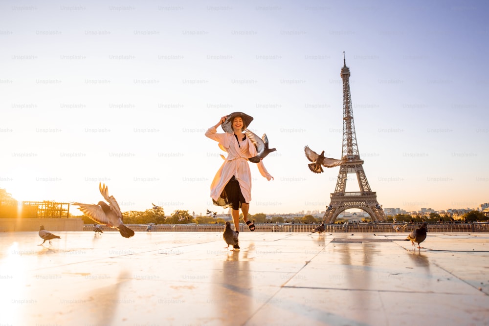 Woman running on the famous square dispersing pigeons with great view on the Eiffel tower early in the morning in Paris