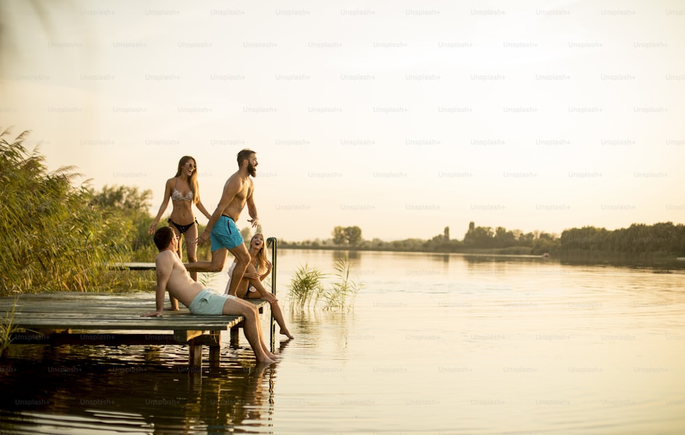 Gruppo di giovani che si divertono sul molo del lago durante la giornata calda dell'hummer