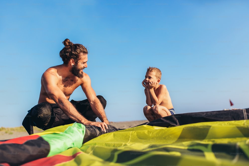 Man surfers with his son in wetsuits with kite equipment for surfing.