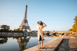 에펠탑에서 풍경을 감상하며 파리의 아침 햇살이 비치는 동안 물에 아름다운 반사를 즐기는 젊은 여성 관광객