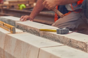 콘크리트 블록을 평평하게 하는 줄자를 가진 실제 건설 노동자.