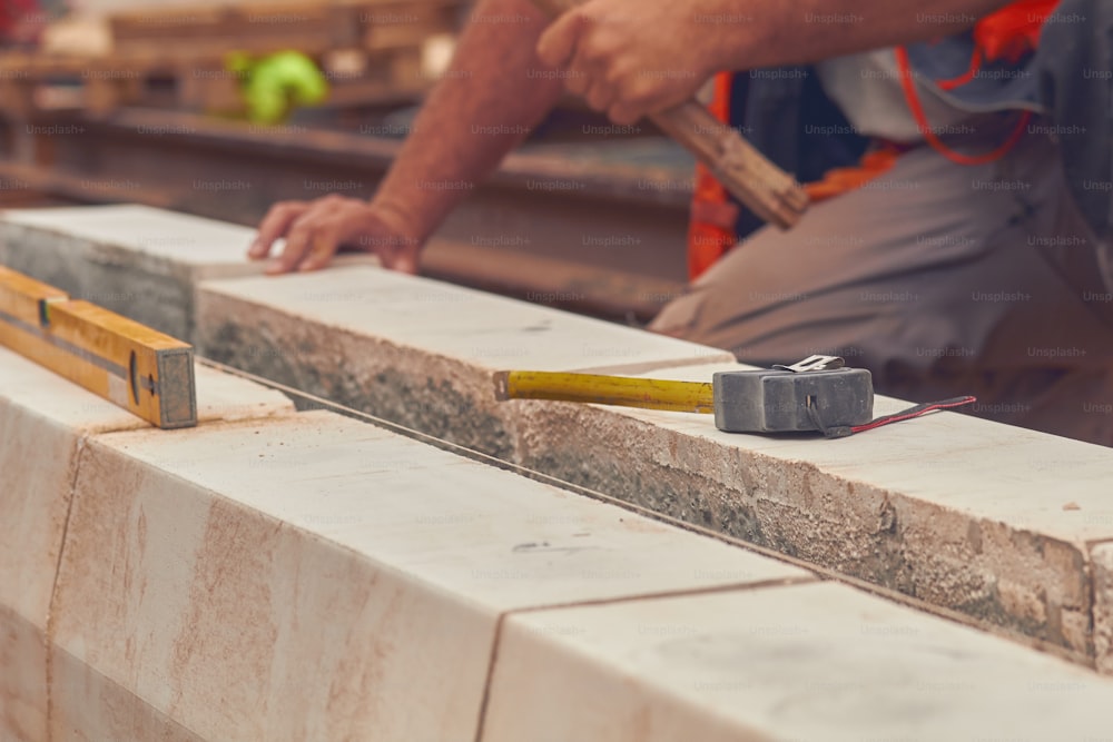 Real construction worker with measuring tape leveling concrete blocks.