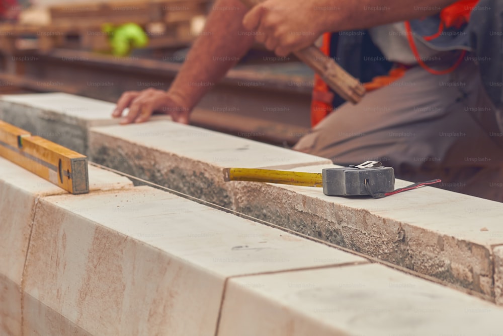 Véritable ouvrier de la construction avec du ruban à mesurer nivelant des blocs de béton.