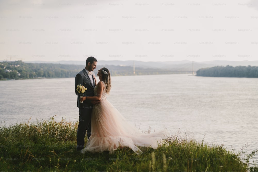 野原に立ってキスをしている夫婦の感情的な写真。背景に川。カップルの目標。