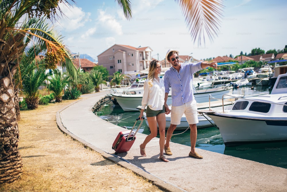 Portrait of two smiling young tourists walking with suitcase