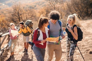 Pequeno grupo de pessoas caminhando e olhando para mapas enquanto está na clareira no outono.