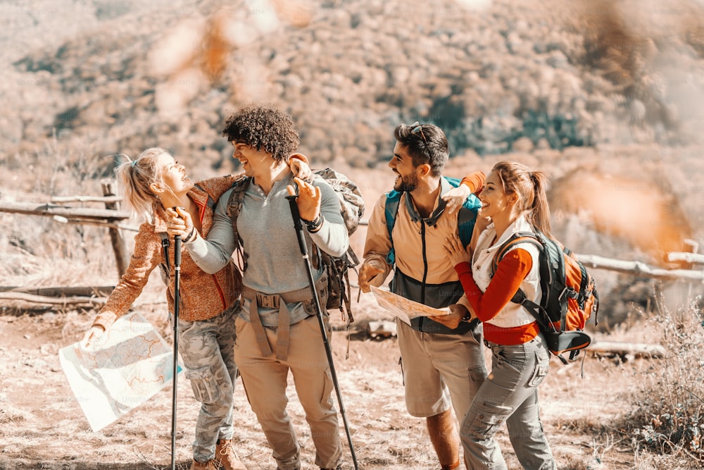 Four happy hikers standing on the glade and enjoying nature in autumn.