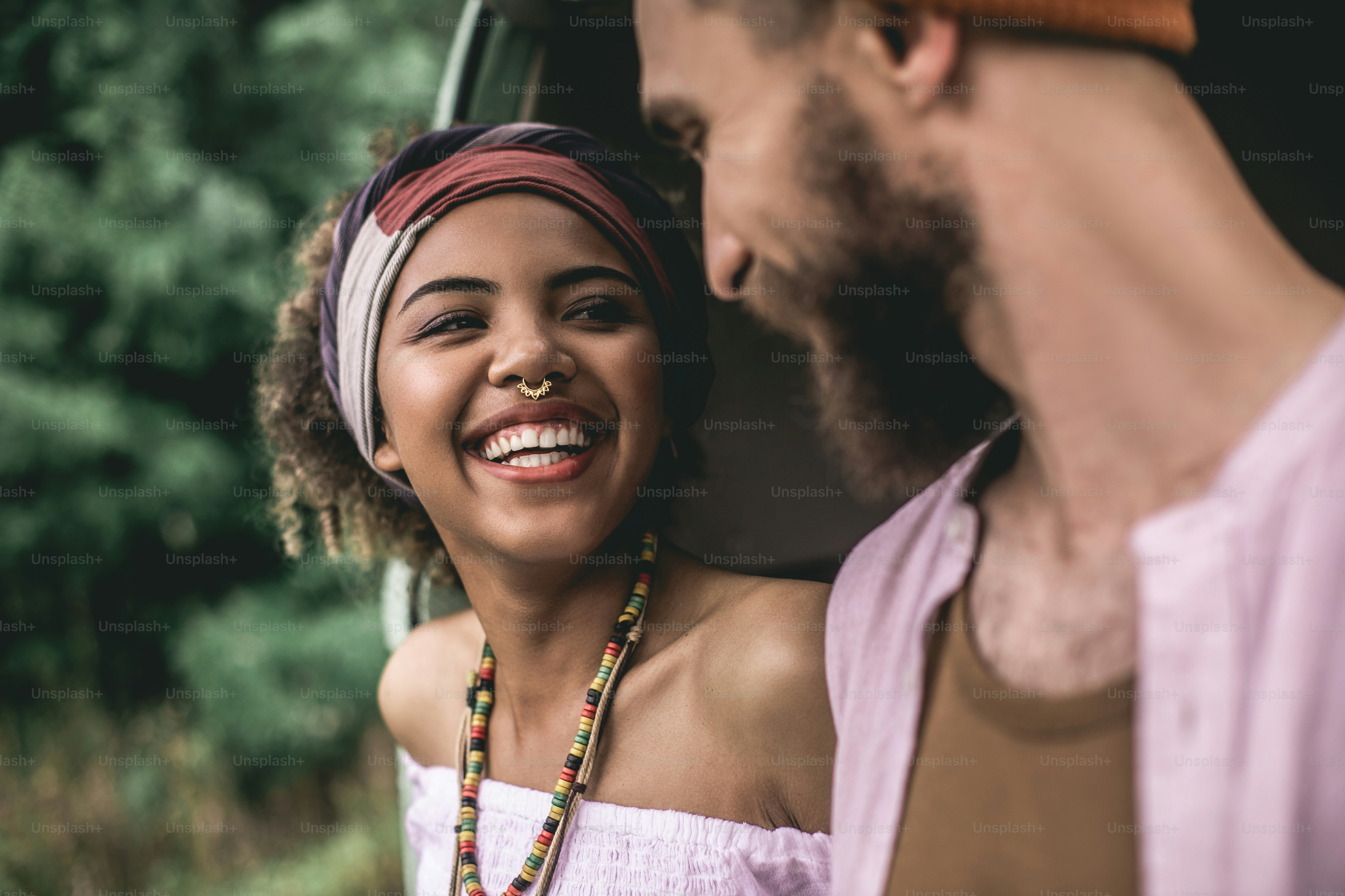 Concept of hippie lifestyle and travel. Close up portrait of cheerful afro-american lady and hipster male looking happy to each other