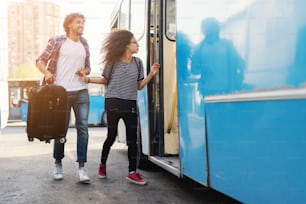 Young multicultural couple rushing to enter the bus. Han holding luggage.