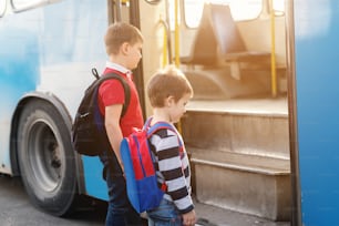 Brothers entering the city bus and going to school. Side view.