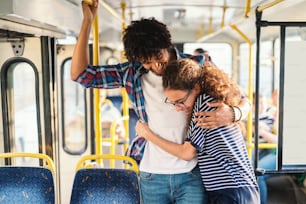 Young multicultural couple hugging in the public transport.