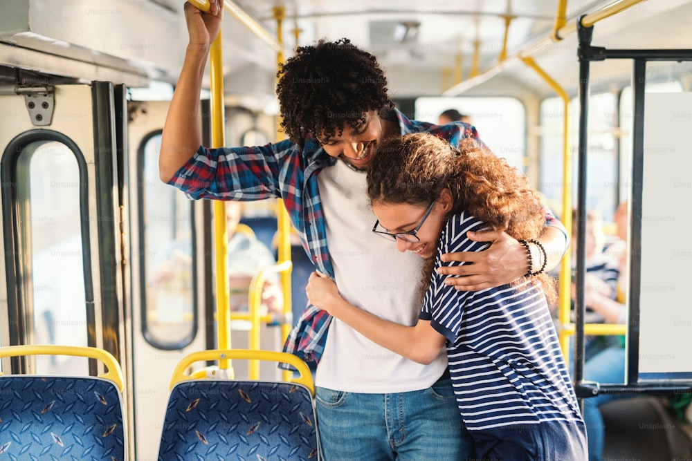 Young multicultural couple hugging in the public transport.