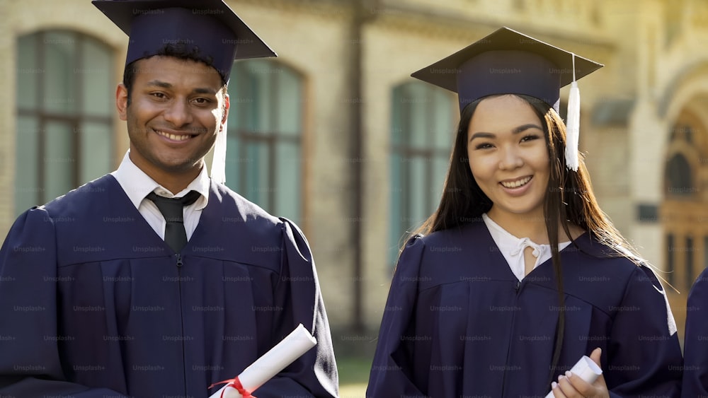 College student in graduation outfit with diplomas smiling, education abroad