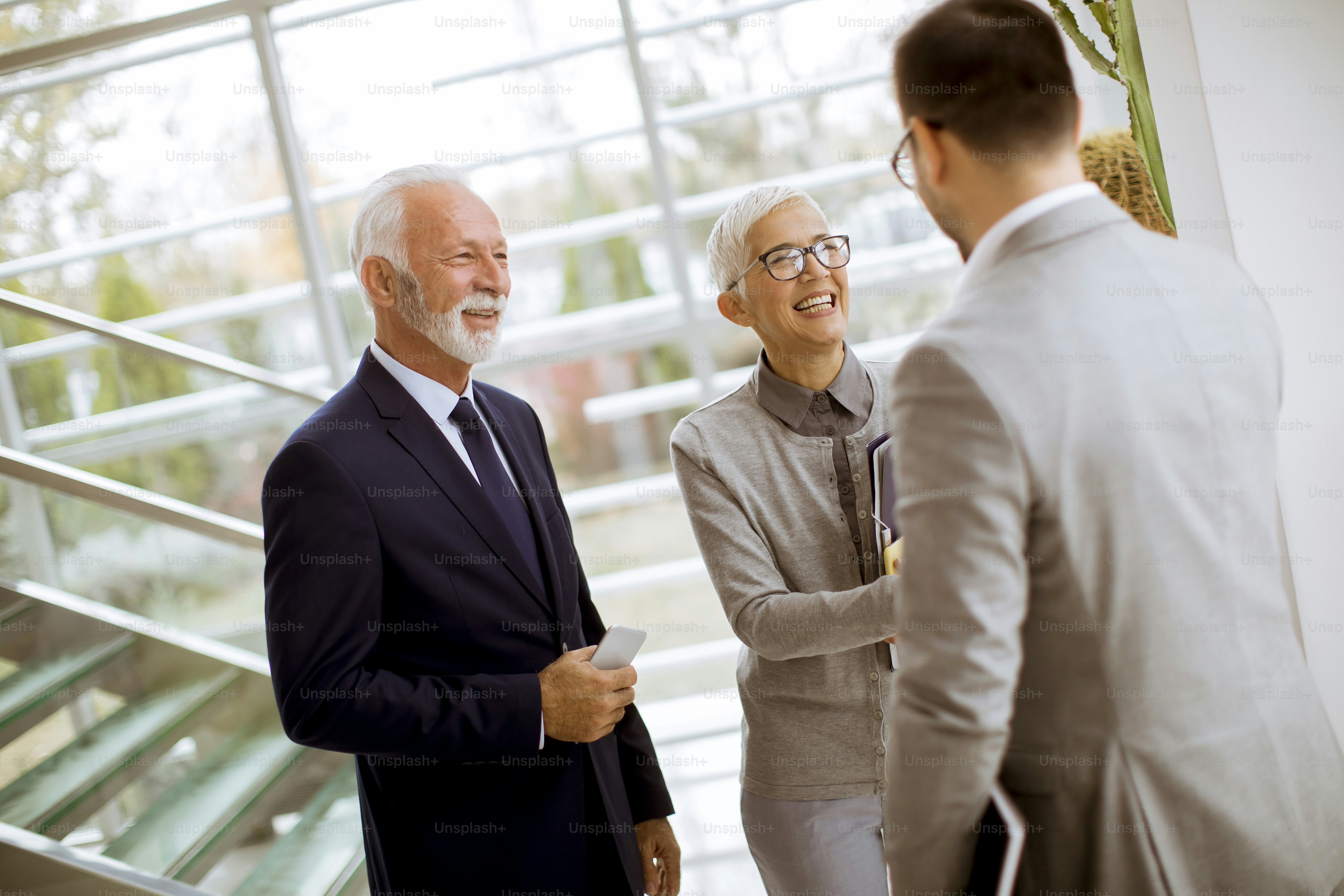 Young businessman with senior clients standing in  modern office